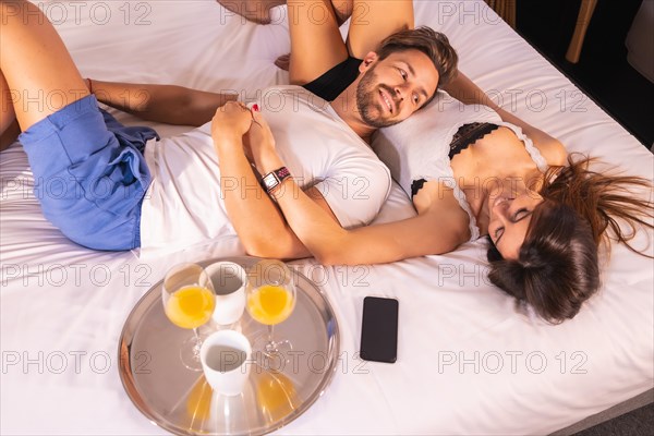A loving couple in pajamas having breakfast in the hotel bed