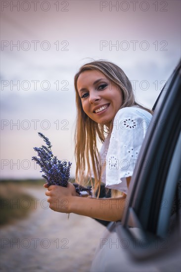 A young blonde Caucasian woman in a white dress in a lavender field. In a field of cultivation of the lavender product in Navarra