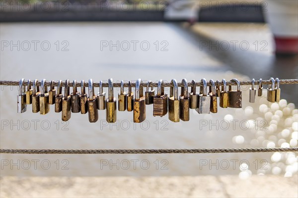 Old rusty padlocks hanging on bridge railing