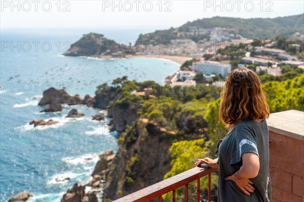 A young tourist looking at Tossa de Mar from the viewpoint in the summer