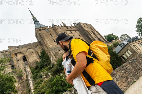 A young father visiting the famous Mont Saint-Michel Abbey in the Manche department