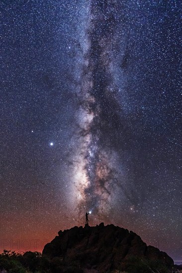 Silhouette of a young man under the stars looking at the lactea way of the Caldera de Taburiente near the Roque de los Muchahos on the island of La Palma