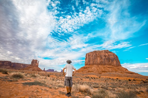 Man with white t-shirt and green hat in the Monument Valley National Park in Three Sisters. Utah