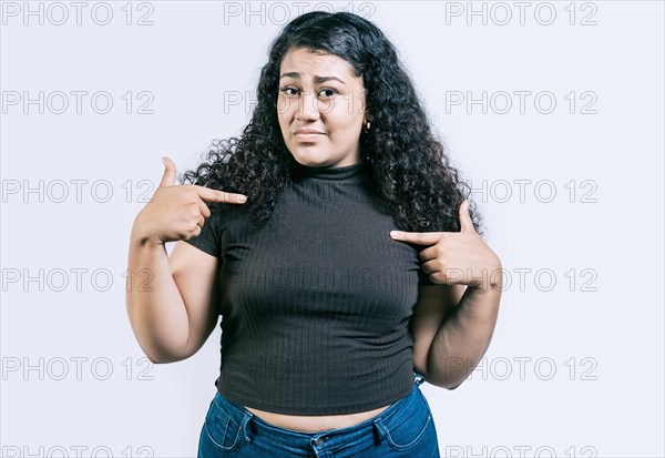 Confused girl pointing at herself isolated. Embarrassed young woman pointing at herself isolated