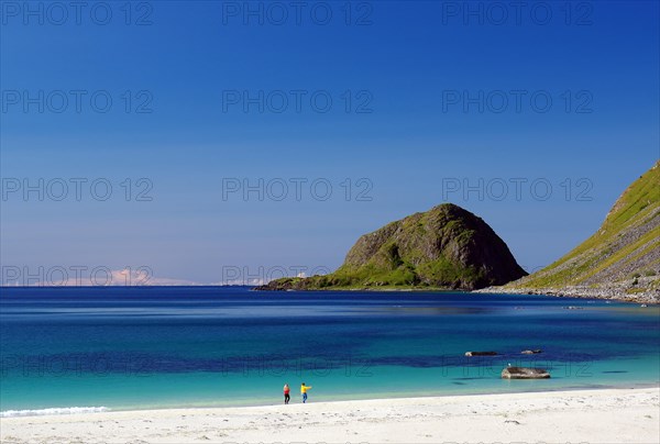 Transparent clear water with two single people on a sandy beach