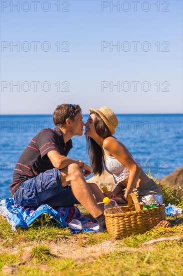 Romantic scene of a Caucasian couple kissing at the picnic in the mountains by the sea enjoying the heat