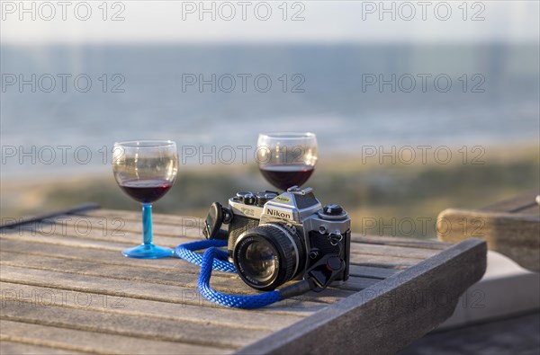 Analogue Nikon camera FE2 and red wine glasses on terrace