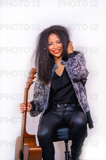 A closeup portrait of a stylish attractive female musician holding an acoustic guitar on her shoulder