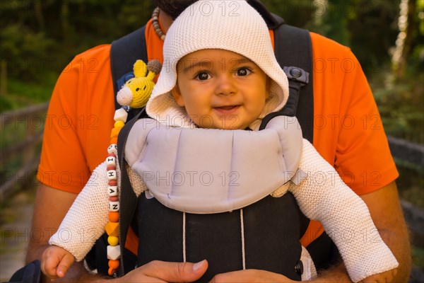 A father with the baby in a backpack heading to Passerelle de Holzarte in the forest or jungle of Irati