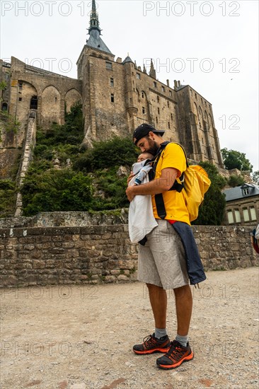 A young father visiting the famous Mont Saint-Michel Abbey in the Manche department