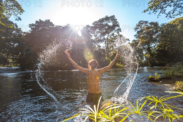 A young woman bathing in the Pulhapanzak waterfall on Lake Yojoa. Honduras