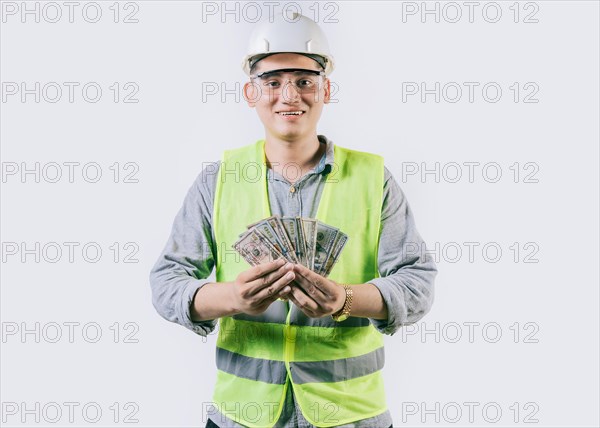 Portrait of happy engineer in helmet holding money isolated. Cheerful male engineer holding money on isolated background