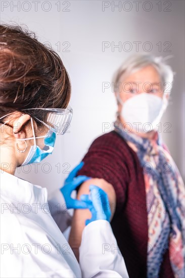 Female doctor injecting the coronavirus vaccine to an elderly lady. Antibodies