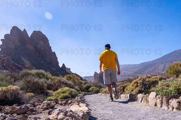 A tourist walking on the path between Roques de Gracia and Roque Cinchado in the natural area of Teide in Tenerife