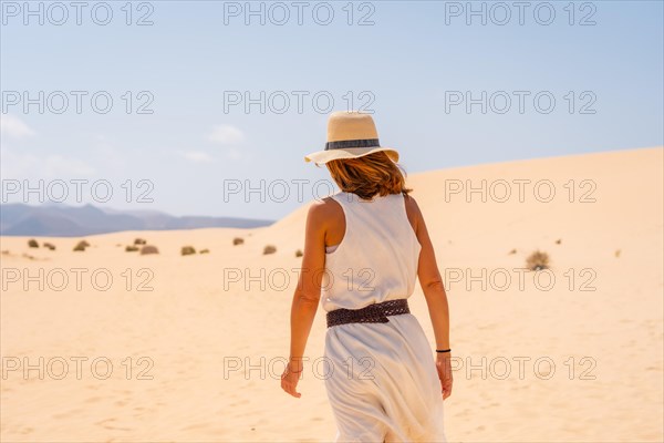 A young tourist wearing a hat walking along the sand on the beaches of the Corralejo Natural Park