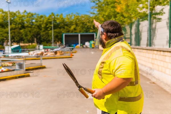 Worker in a recycling factory or clean point and garbage with a face mask and plastic protective screen