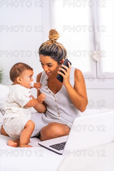 Young Caucasian mother with her son in the room on top of the bed. Mother teleworking and caring for her child