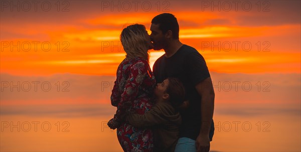 Romanticism on the top of a mountain A young couple kissing next to their son. Adventure lifestyle A summer afternoon in the mountains of the Basque country