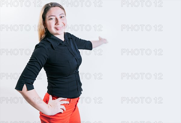 Smiling latin woman welcoming you isolated. Cheerful people pointing a promotion with her palm. Happy young girl pointing back presenting a product