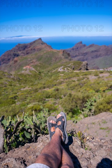 A young man sitting looking at the mountain town of Masca in the north of Tenerife