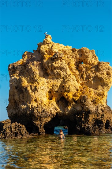 A tourist in the water next to the rocks at Praia dos Arrifes