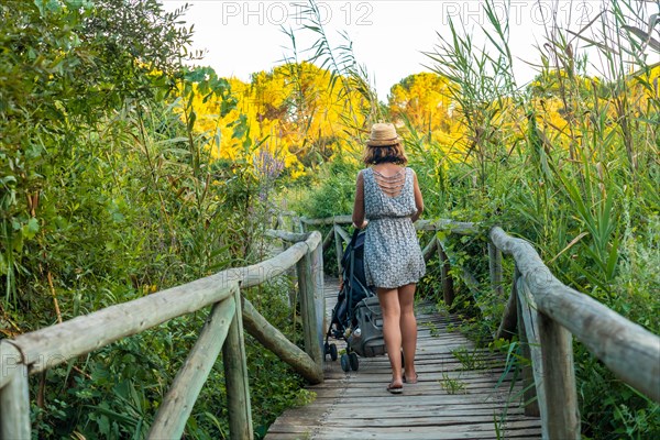 A young woman walking with her son along the wooden walkway in the Donana Natural Park