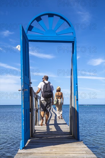 A couple at a blue door on the beach of Sandy Bay on Roatan Island. Honduras