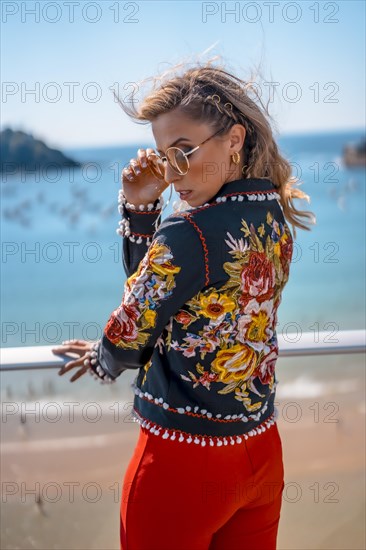 Portrait of a blonde woman on a terrace enjoying summer vacations with the sea in the background