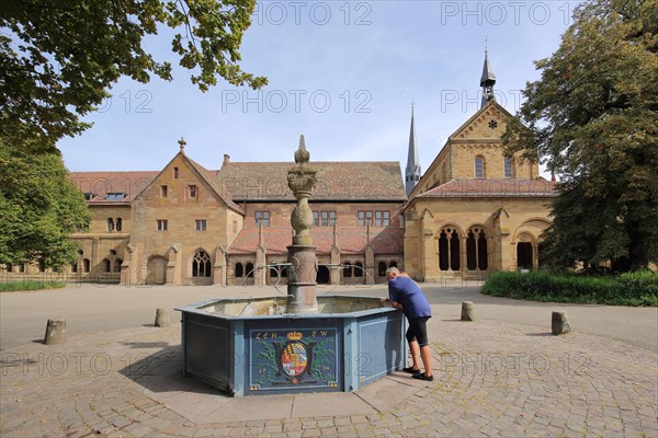 Romanesque monastery church and fountain with coat of arms of Wuerttemberg Duke Ludwig