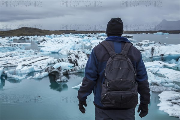 A young tourist with backpack on the frozen lake of Joekulsarlon in August. Iceland