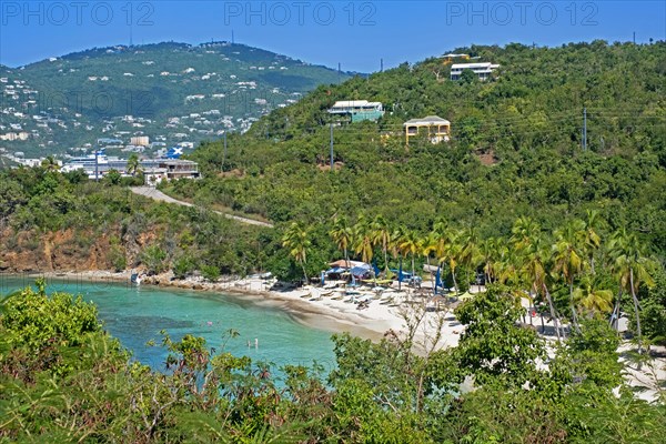 Tourists on white sandy beach with palm trees along Druif Bay at Water Island