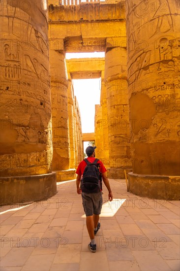 A young man strolling between the hieroglyphic columns of the Temple of Karnak