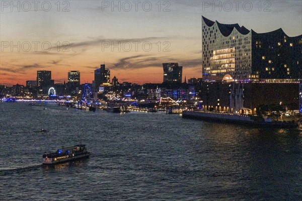 Harbour cruise ship and Elbe Philharmonic Hall illuminated in the evening