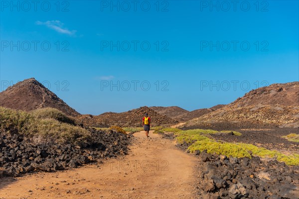 A young man with a yellow backpack on the trail heading north to Isla de Lobos