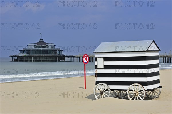Striped beach cabin on wheels and seaside pier of Blankenberge