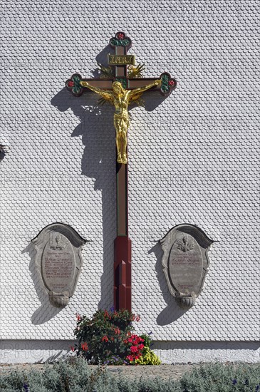 Wooden shingle wall with crucifix and floral decoration