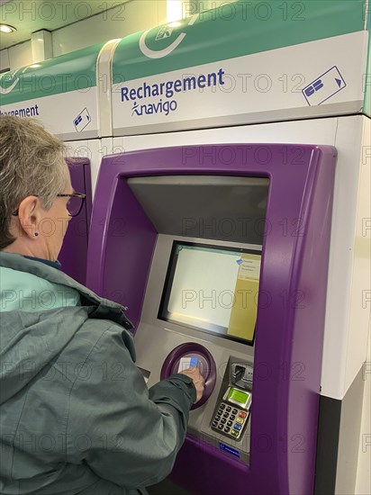 Elderly woman charging her smart card at a charging station for the Navigo Easy Travel Card