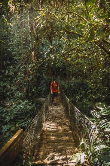 A young man walking along a beautiful wooden bridge in the Cerro Azul Meambar National Park