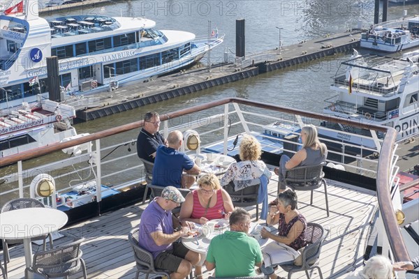 Passengers sitting at tables on the Lido Deck of the cruise ship Vasco da Gama moored at the Ueberseebruecke in the Port of Hamburg