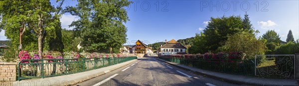 Village entrance over a bridge with lush flowers to Fouday