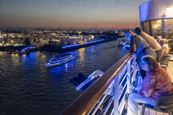 Passengers sit on the Lido Deck of the cruise ship Vasco da Gama and watch the Blue Port light art event in the harbour