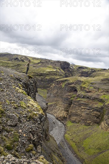A young man on a cliff in the Landmannalaugar valley on the trek. Iceland