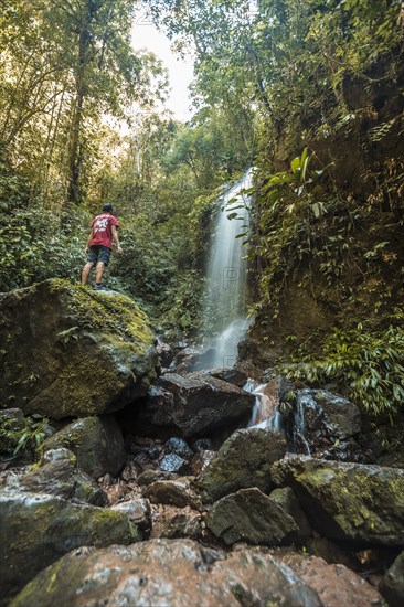 A boy with his arms raised in the Waterfall of the Cerro Azul Meambar National Park