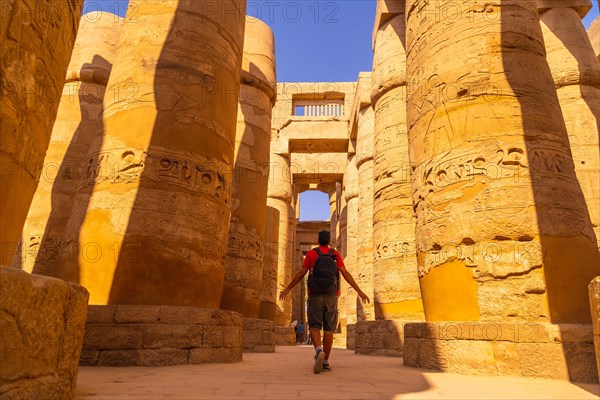 A young man walking between the columns with hieroglyphs inside the Karnak Temple