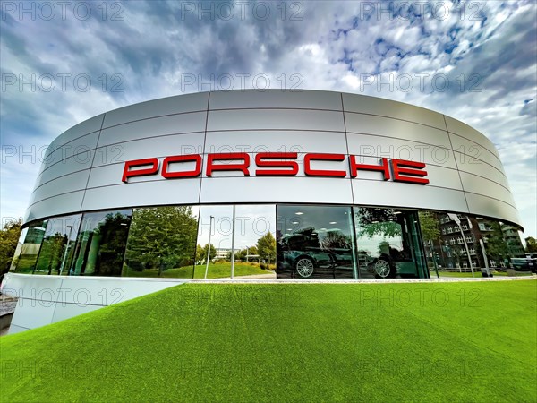 View of futuristic looking building with typical reduced architecture of showroom sales house of car brand car manufacturer Porsche with lettering Porsche at representation of car dealer Gottfried Schultz sales of sports cars brand Porsche