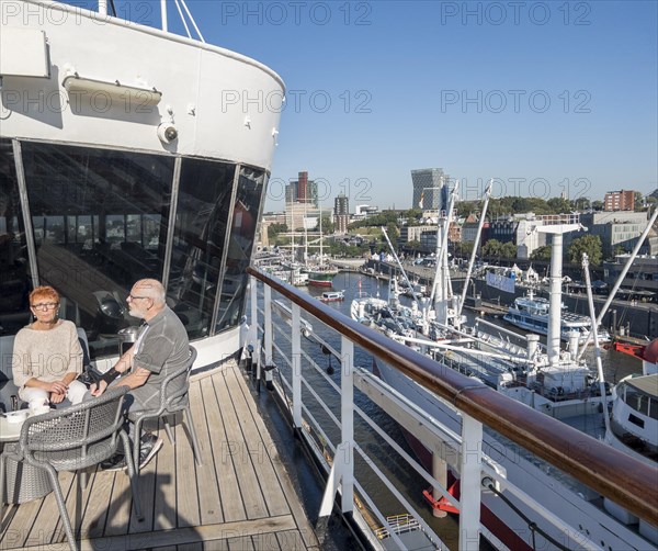 Passengers sitting at a table on the Lido Deck of the cruise ship Vasco da Gama moored at the Ueberseebruecke in the Port of Hamburg