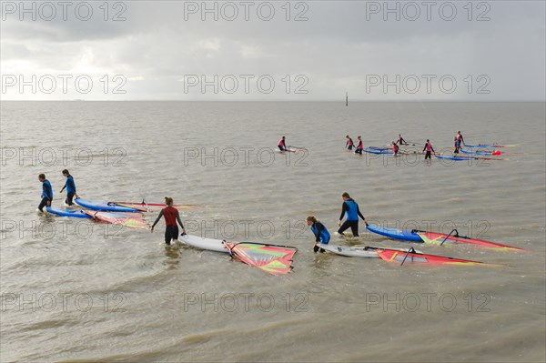 Surfers of a surf school pull the surfboard through the sea in the rain