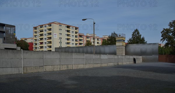 Visitors to the Wall memorial look through slits between the concrete elements at the former death strip