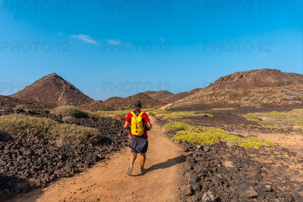 A young man with a yellow backpack on the trail heading north to Isla de Lobos