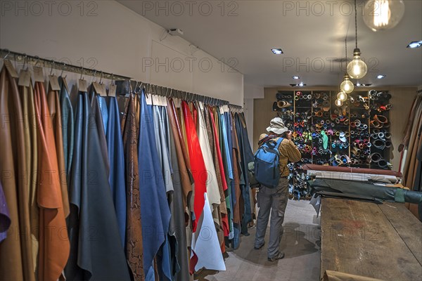 Tourist taking pictures of the leather shelves in a saddlery with permission